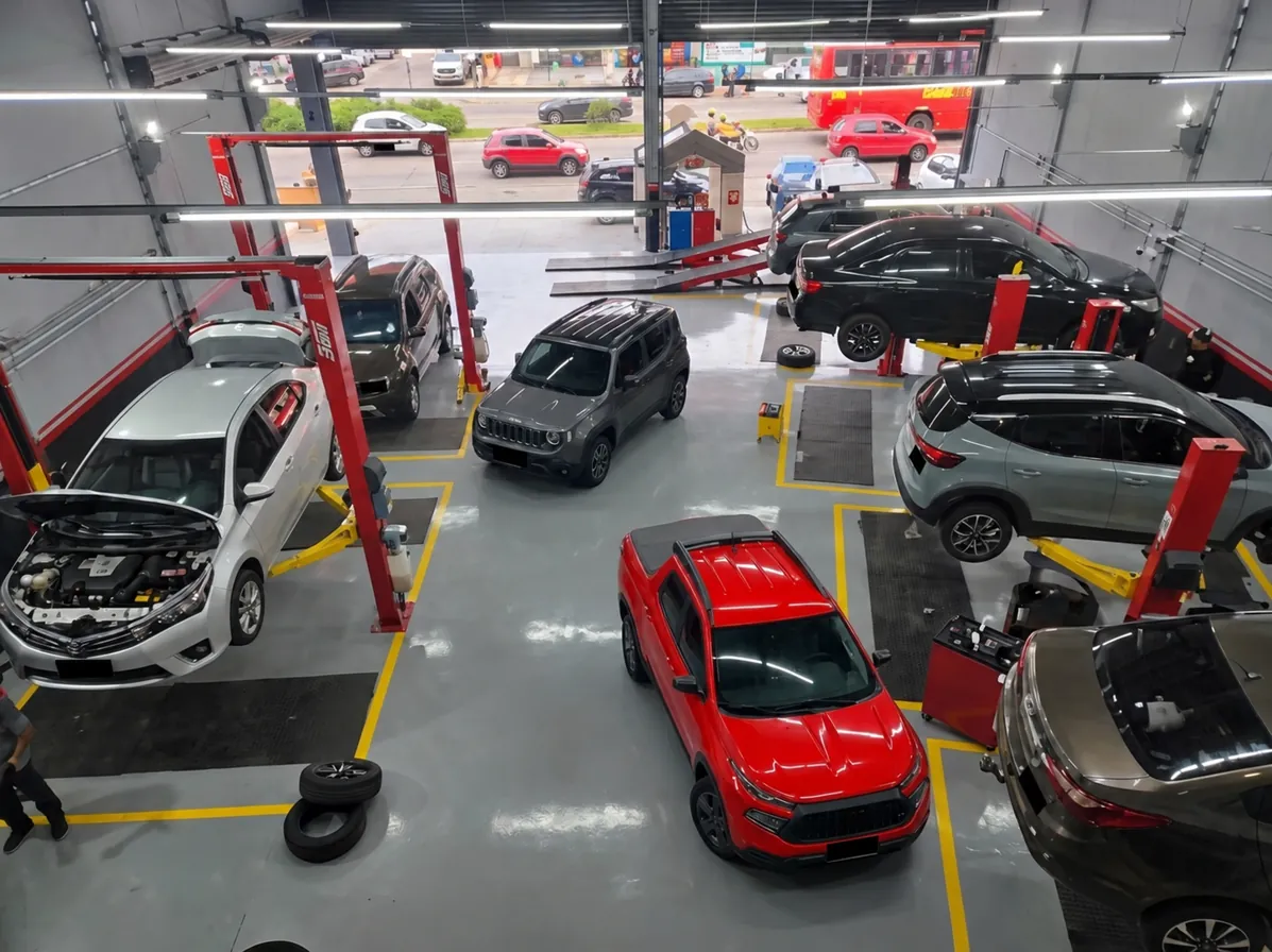 Jeep cinza e Fiat Toro vermelha no interior da Êxito Autocenter, com placas ocultadas